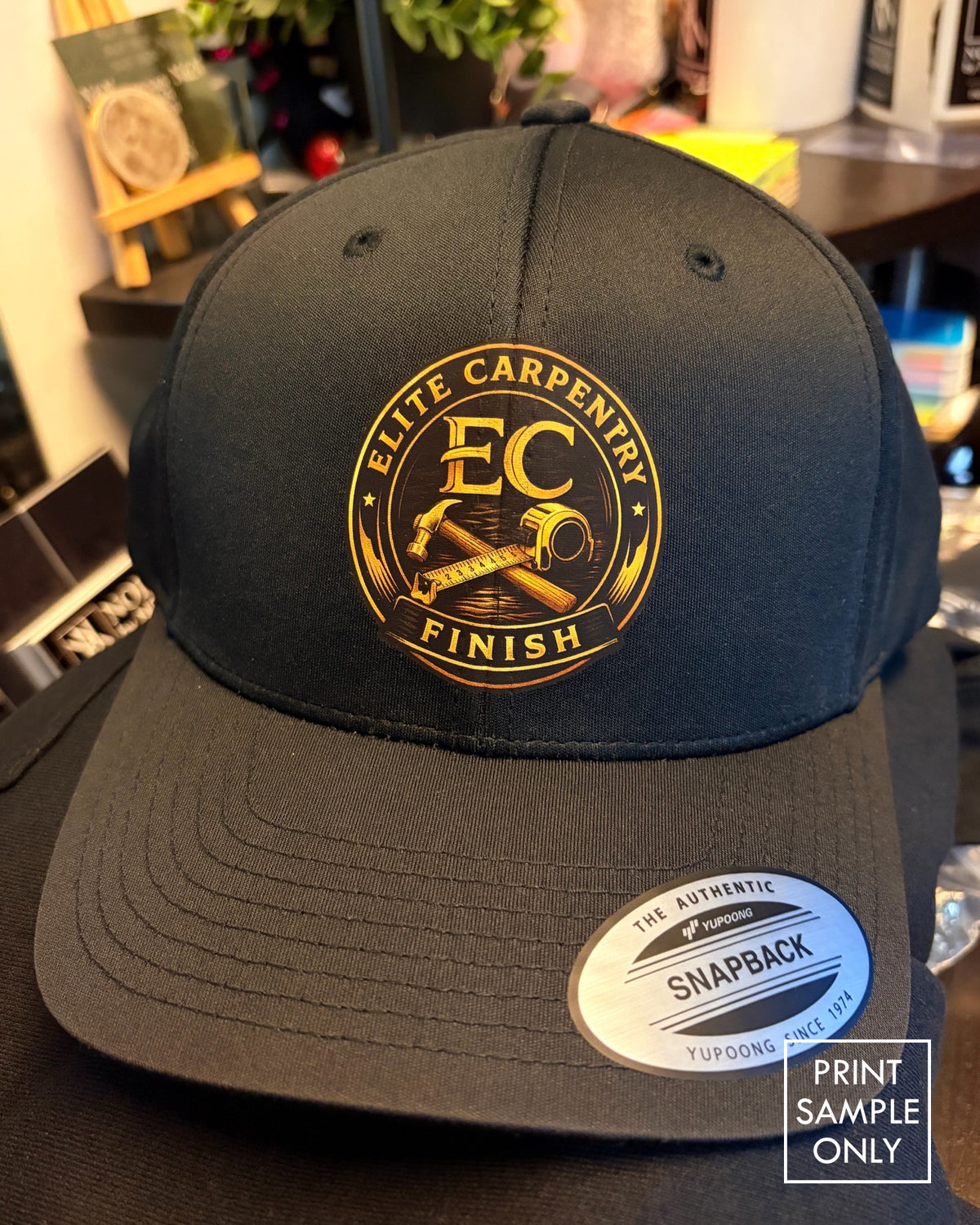 Sample print on a black snapback cap: gold crest logo (print sample only)