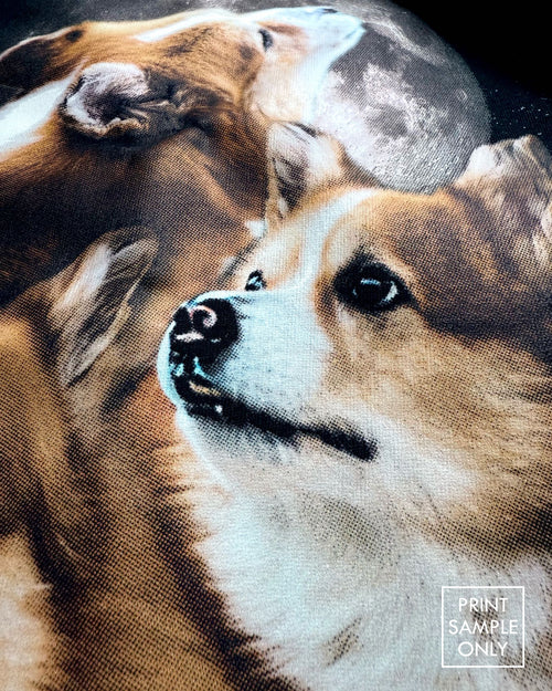 Close-up of a sample print on black fabric: corgis and moon artwork (print sample only)