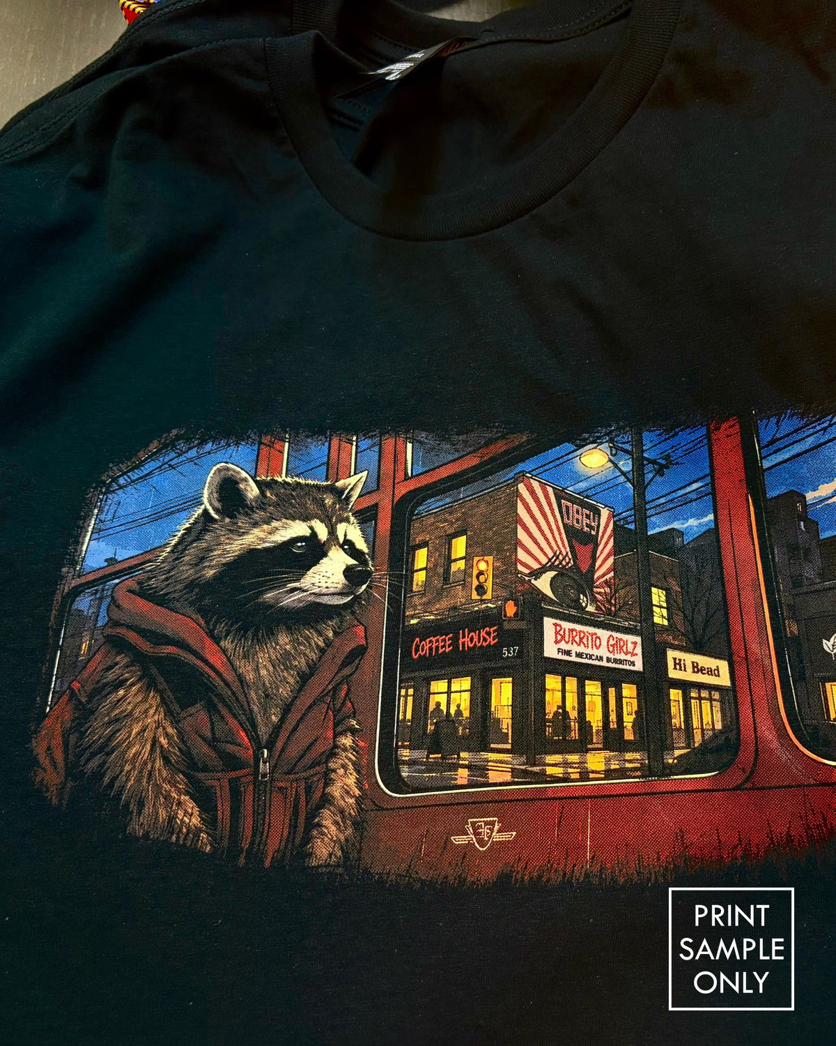 Sample print on a black t-shirt: raccoon on a streetcar (print sample only)